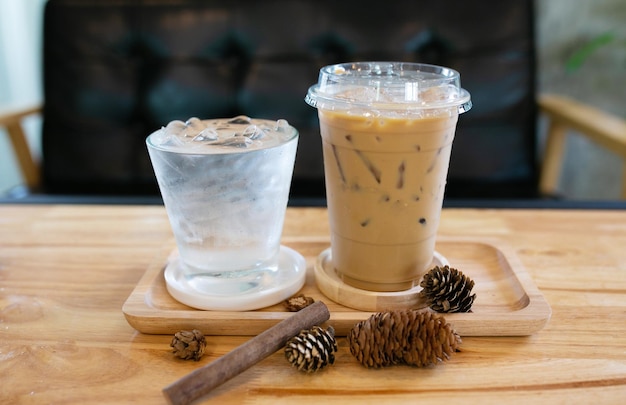 Glass of cool water and cool coffee on wooden table in coffee shop background