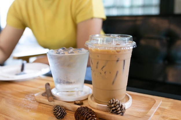 Glass of cool water and cool coffee on wooden table in coffee shop background.