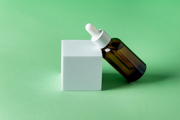 Glass Cosmetic Bottles Lying on White Podium on Green Background Scene with Geometric Shapes