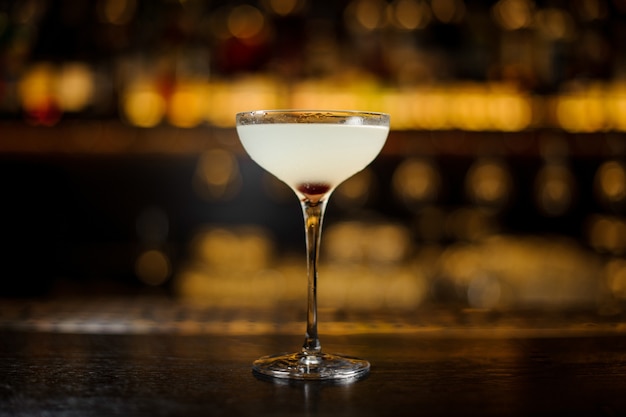 Glass of a Courpse Reviver cocktail on the wooden steel bar counter