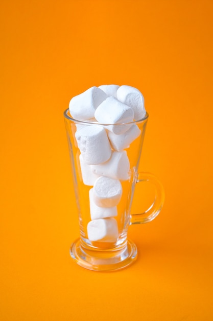 Glass cup bottle with marshmallows on a yellow background. Creative concept. Copy space. drinking straw