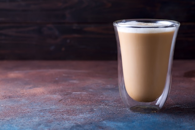 Glass cup of coffee latte on stone dark table