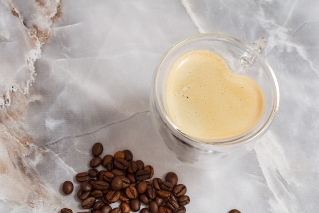 Glass cup of coffee in shape of a heart and roasted coffee beans on the kitchen table