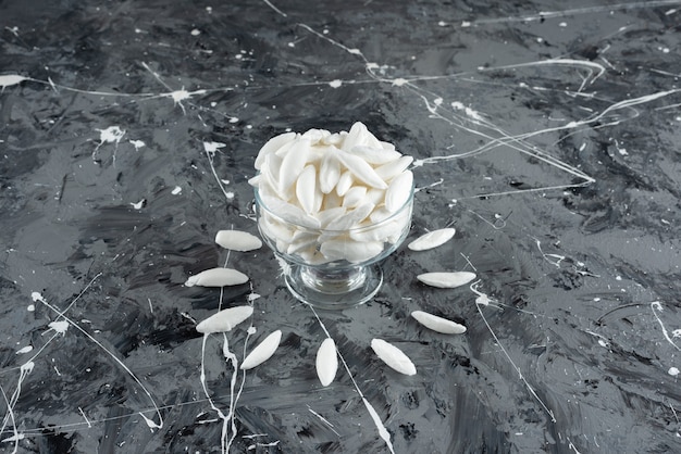 A glass cup full of mint white candies on a marble surface