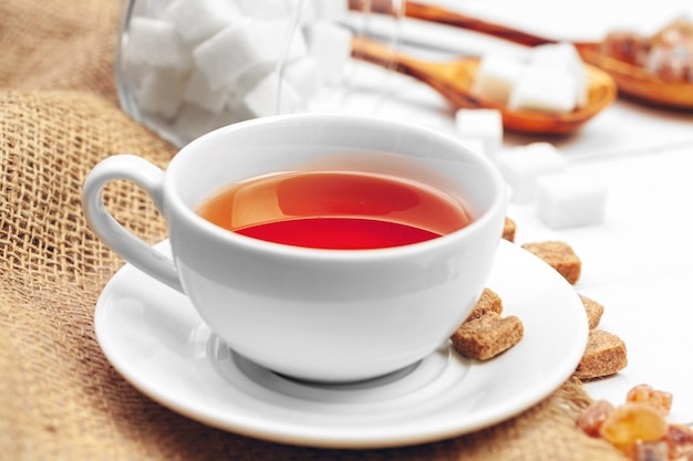 Glass cup of hot tea with sugar on the table