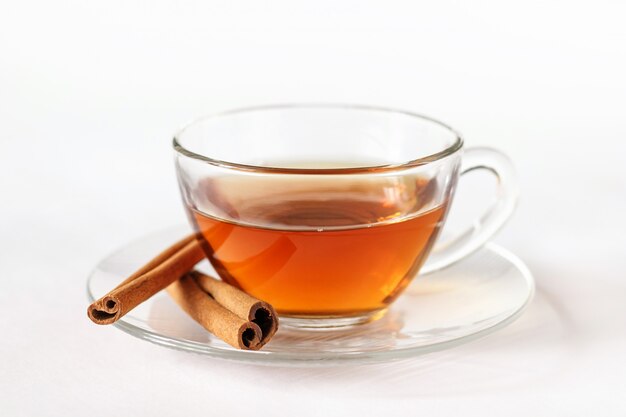 Glass cup of tea with cinnamon sticks.