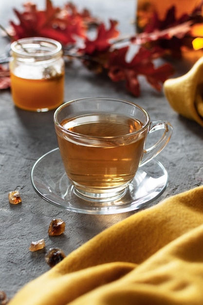 A glass cup of tea with honey on gray table