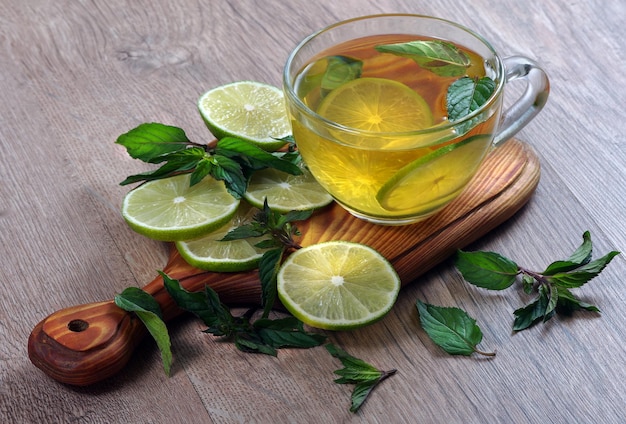 a glass cup of tea with lemon and mint leaves.