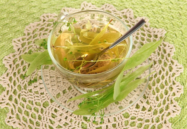 Glass cup of tea with linden on napkin closeup