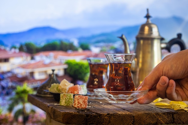 Glass Cup of turkish tea served in traditional style with summer outdore view