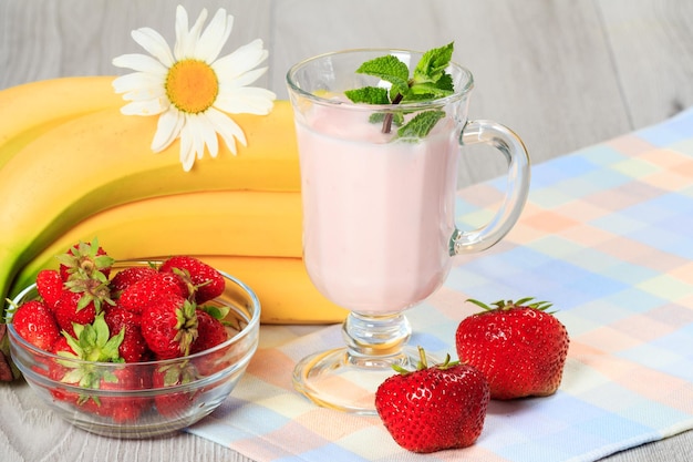 Glass of delicious yogurt with mint and fresh strawberries banana chamomile