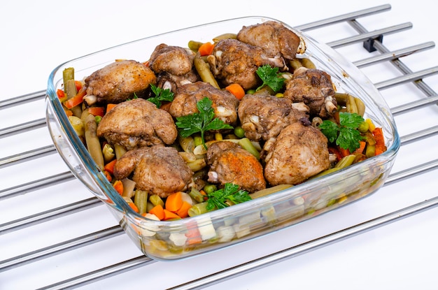 Glass dish with baked vegetables and chicken pieces. Studio Photo