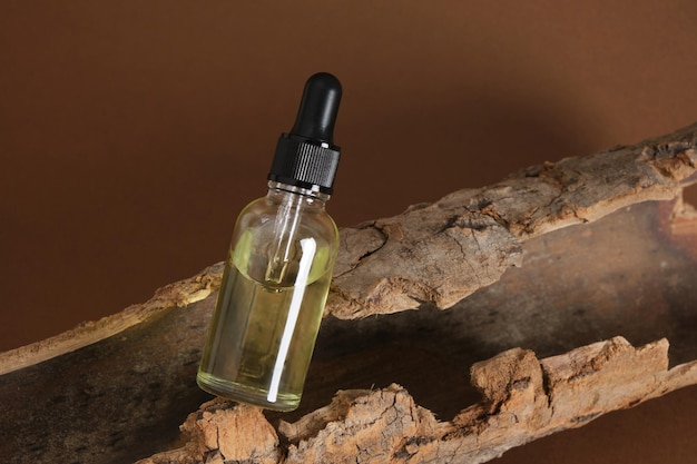 Glass dropper bottle with serum or oil on the bark