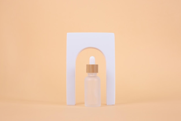 Glass dropper bottles with arch on beige background