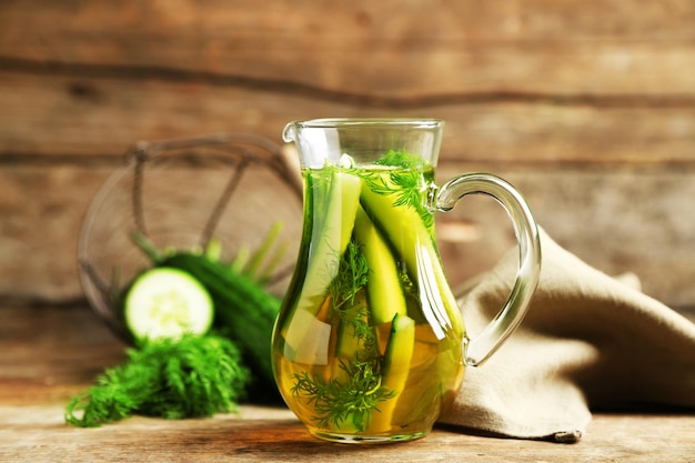 Glass ewer with fresh organic cucumber water on wooden table