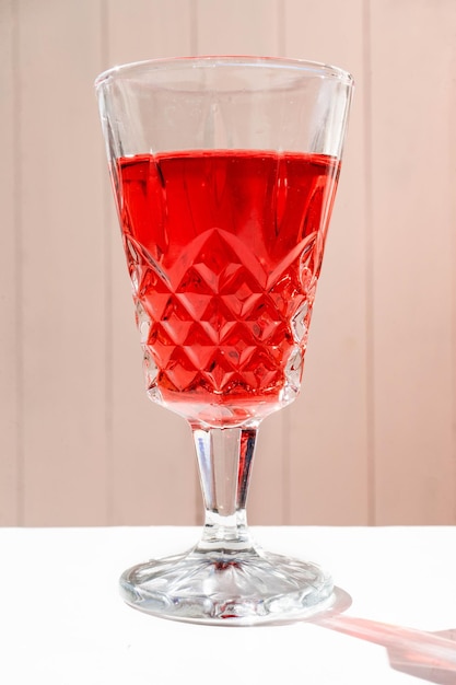 Glass of an exquisite red cocktail on a white surface