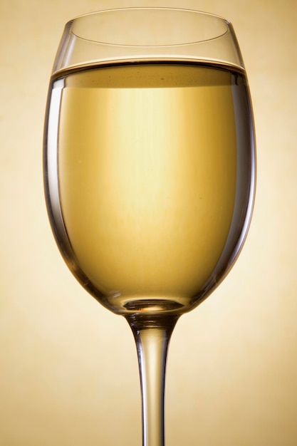 a glass filled with white wine on a gold background