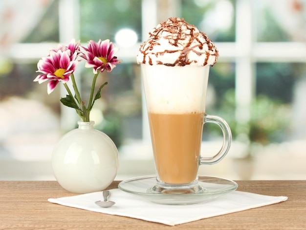 Glass of fresh coffee cocktail and vase with flower on wooden table closeup