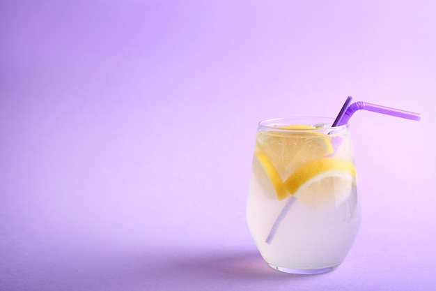 Glass of fresh lemonade on color background