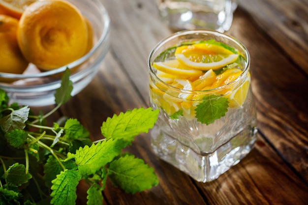 Glass of fresh lemonade with lemon and mint on wooden background