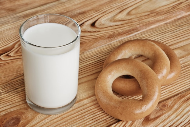 Glass of fresh milk and three bagels on wooden table Morning breakfast concept