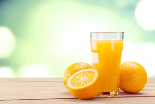 Glass of fresh orange juice on blurred light background