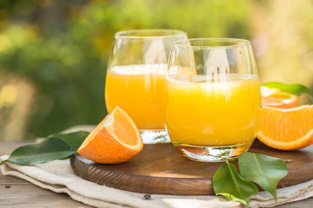 Glass of fresh orange juice,ripe orange fruit and slices on natural .Freshly squeezed orange juice with drinking straw,orange fruit and orange slices.