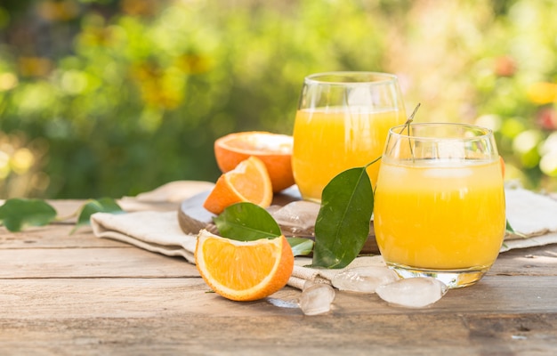 Glass of fresh orange juice,ripe orange fruit and slices on natural .Freshly squeezed orange juice with drinking straw,orange fruit and orange slices.