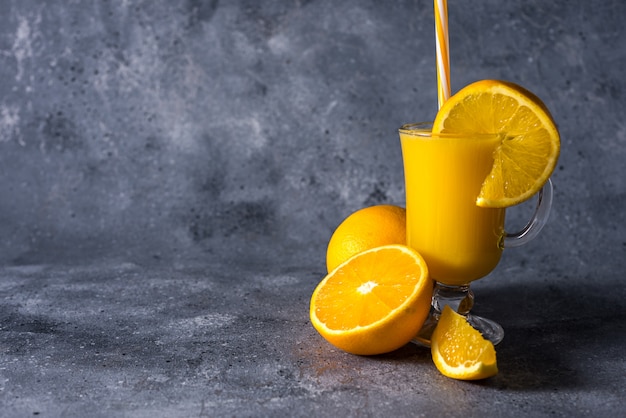 Glass of fresh orange juice, ripe orange fruits and slices