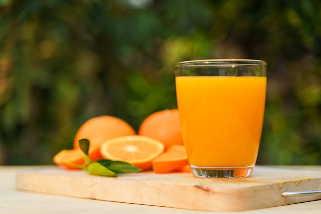 Glass of fresh orange juice with fresh fruits on wood