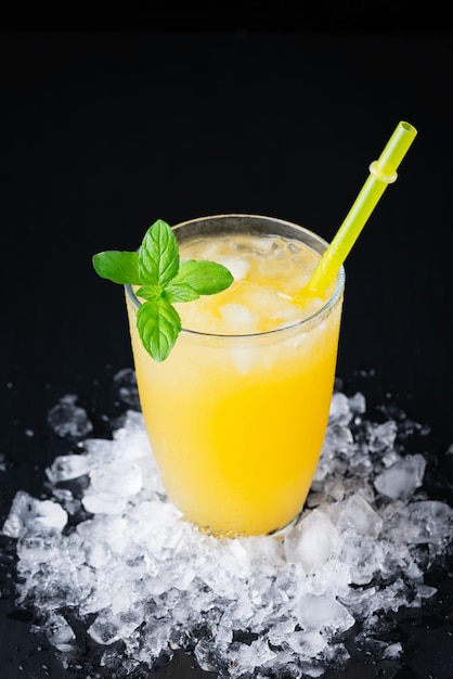 Glass of fresh orange juice with ice on a black background with a place for inscription