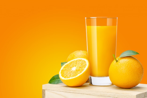 Glass of fresh orange juice on wooden box, Fresh fruits Orange juice in glass with group on orange color background with copy Space for your text.