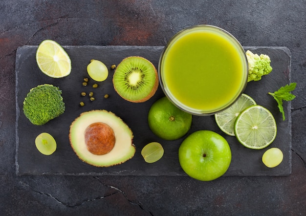 Glass of fresh raw organic green toned fruit and vegetables. Avocado, lime, apple, kiwi and grapes with broccoli and cauliflower