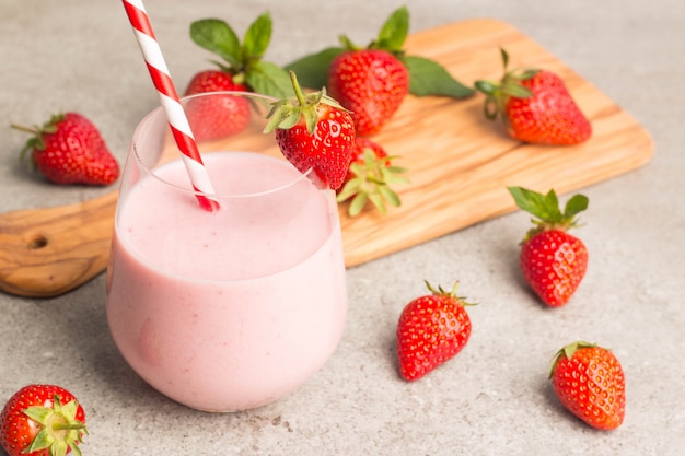 A glass of fresh strawberry milkshake on pink background