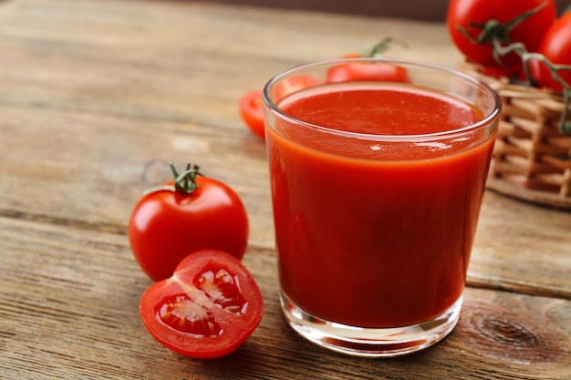 Glass of fresh tomato juice on wooden background