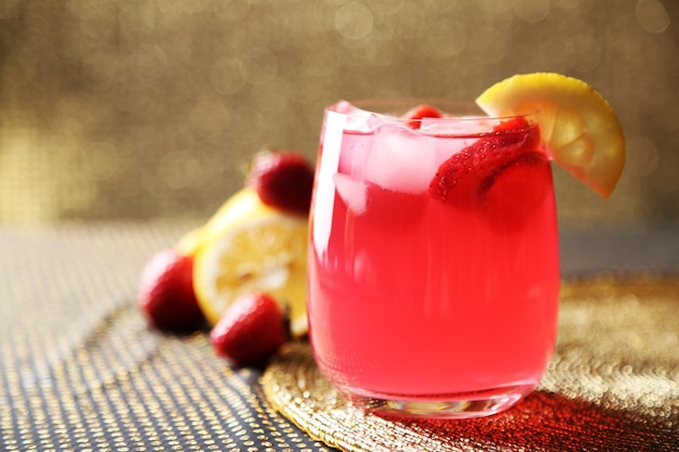 Glass of freshness lemonade with strawberries on bright background