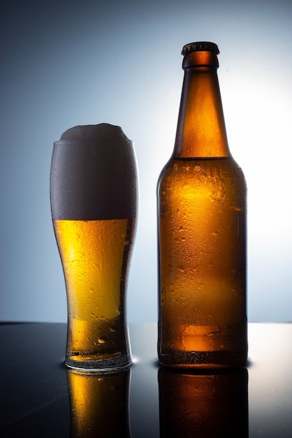 glass of frothy beer with fresh beer bottle on a table