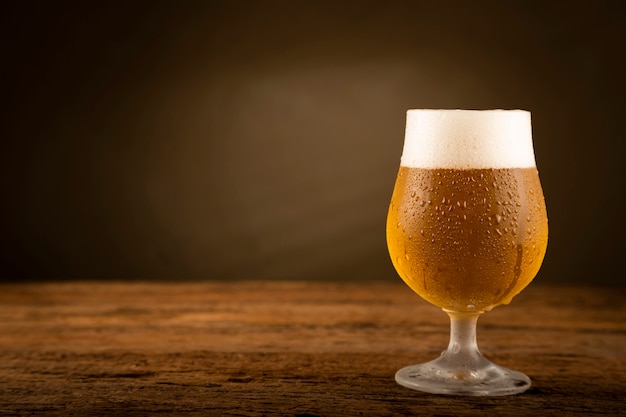 Glass full of cold beer on the wooden table