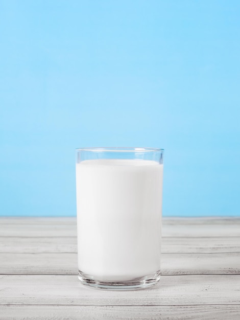 The glass full of milk on wooden table Glass of fresh white milk on blue background in the kitchen