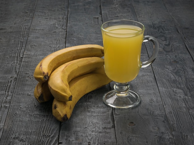 A glass glass on a stem with smoothies and bananas on a rustic background Flat lay