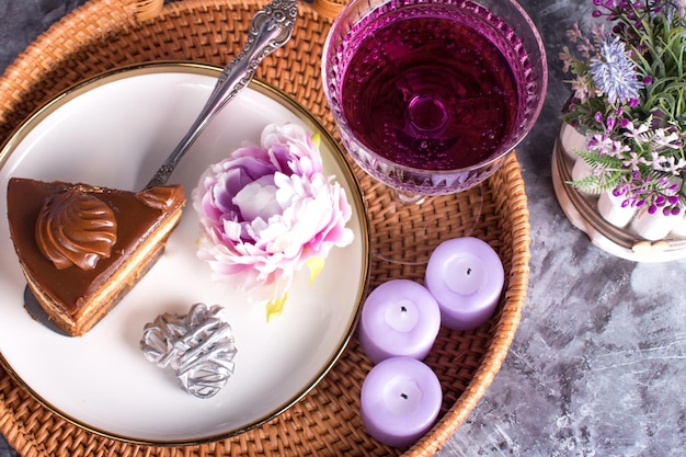 A glass glassa creamer for drinks with colored drinks Alcoholic fruit cocktail on a wicker tray on a wooden background and a plate of sweet cake with condensed milk relaxation concept