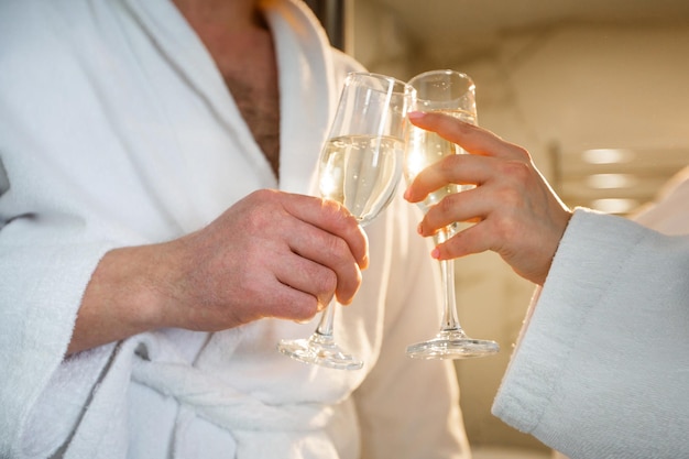 glass glasses with champagne in the hands of a happy couple in white coats