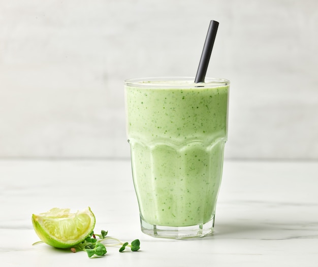 Glass of green healthy breakfast smoothie on kitchen table