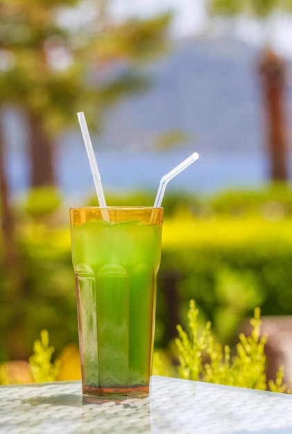 A glass of green liquid with a straw in it