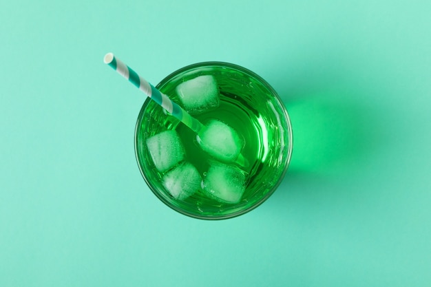 Glass of green soda on mint surface