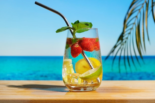 Glass of hard seltzer cocktail on tropical summer beach