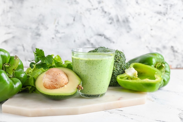 Glass of healthy smoothie with different vegetables on light surface