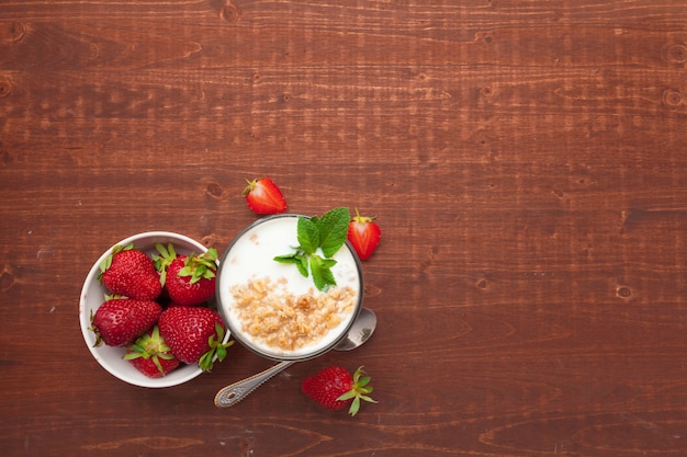 Glass of healthy strawberry yogurt with fresh berries on wooden table top view