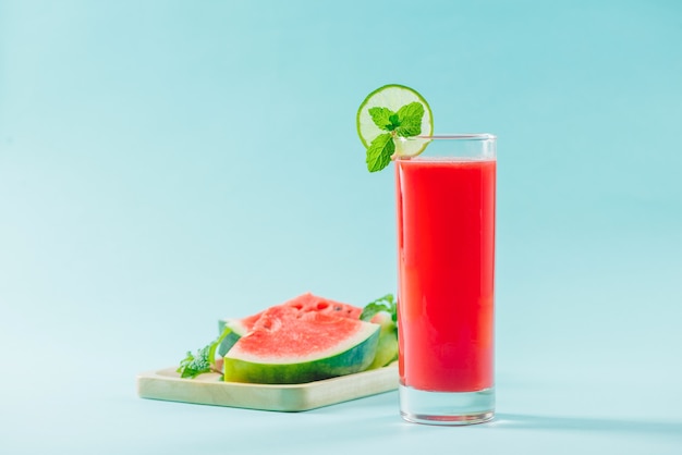 Glass of healthy watermelon juice in summertime on blue background.