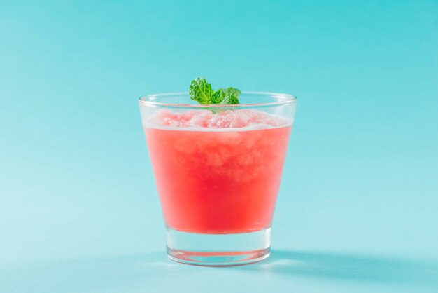 Glass of healthy watermelon juice in summertime on blue background.